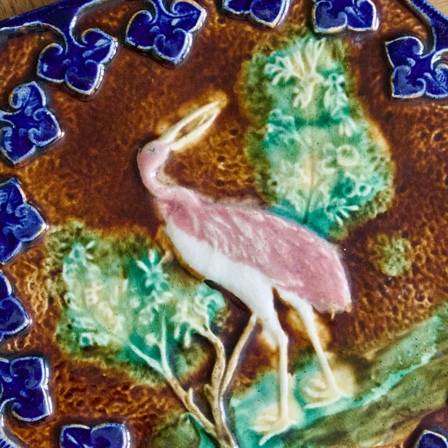 Dessous de plat XIXe en barbotine polychrome oiseau rose