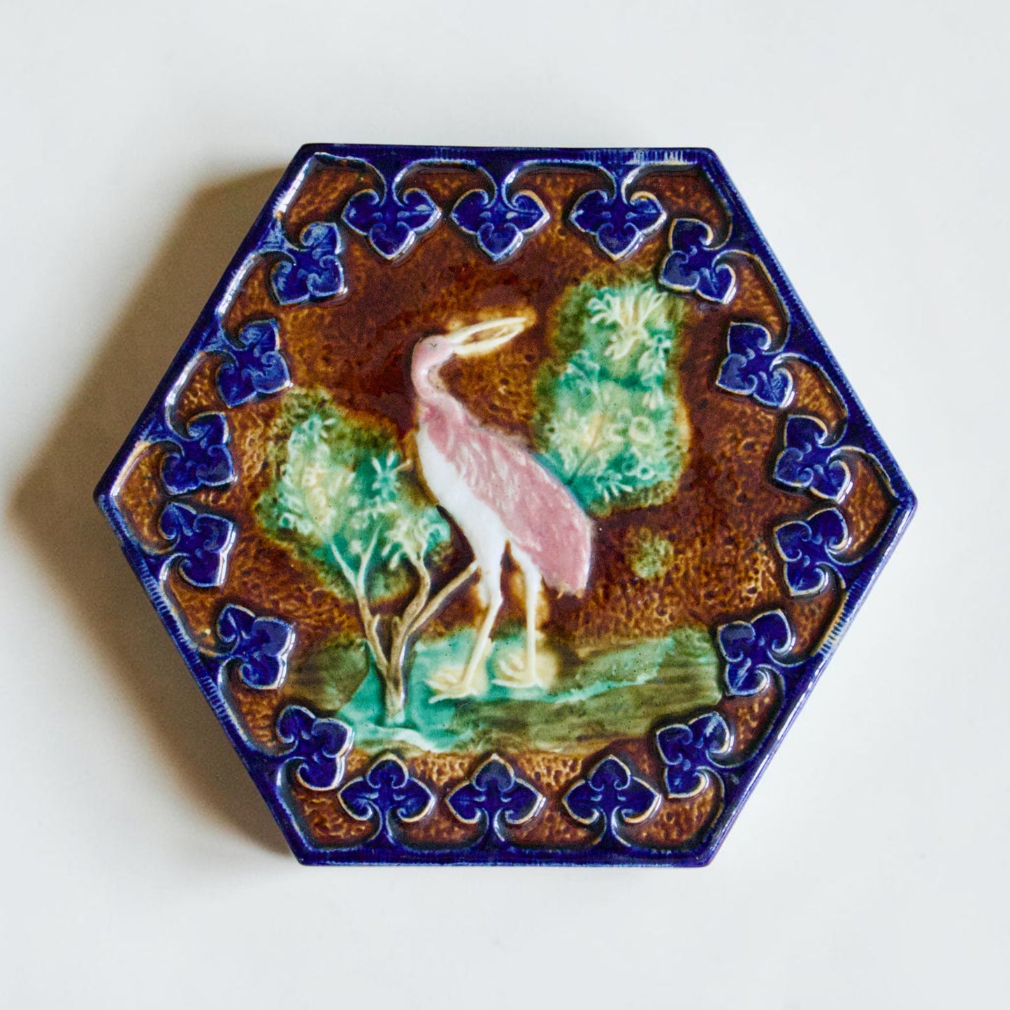Dessous de plat XIXe en barbotine polychrome oiseau rose