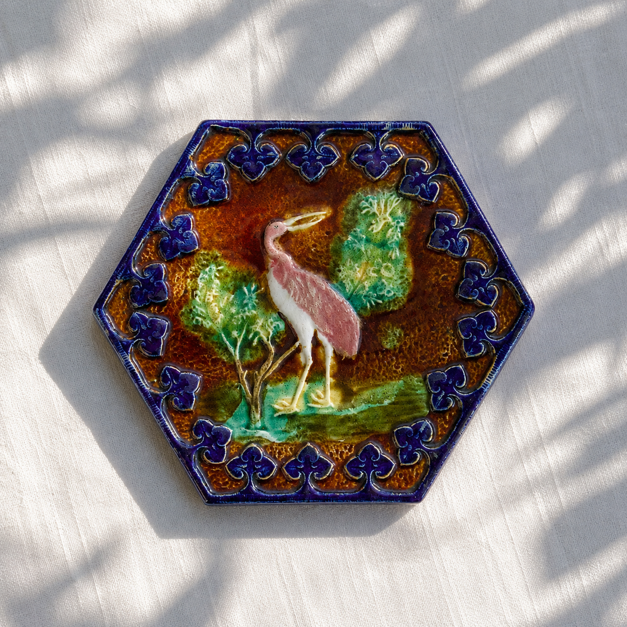 Dessous de plat XIXe en barbotine polychrome oiseau rose