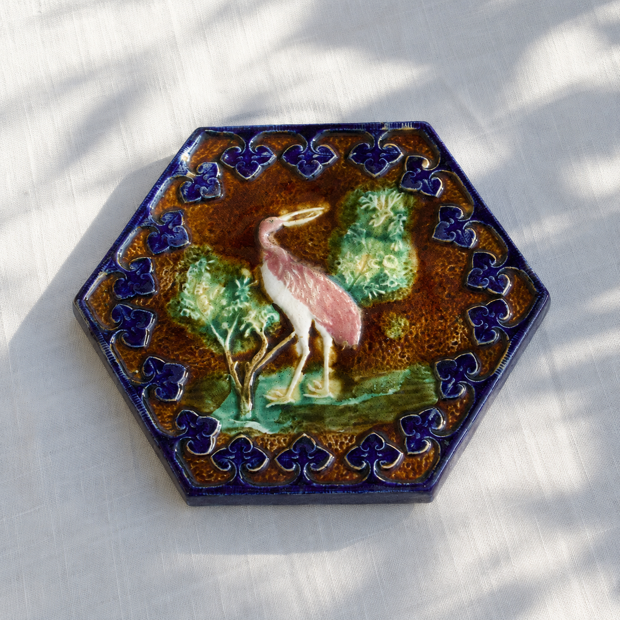 Dessous de plat XIXe en barbotine polychrome oiseau rose
