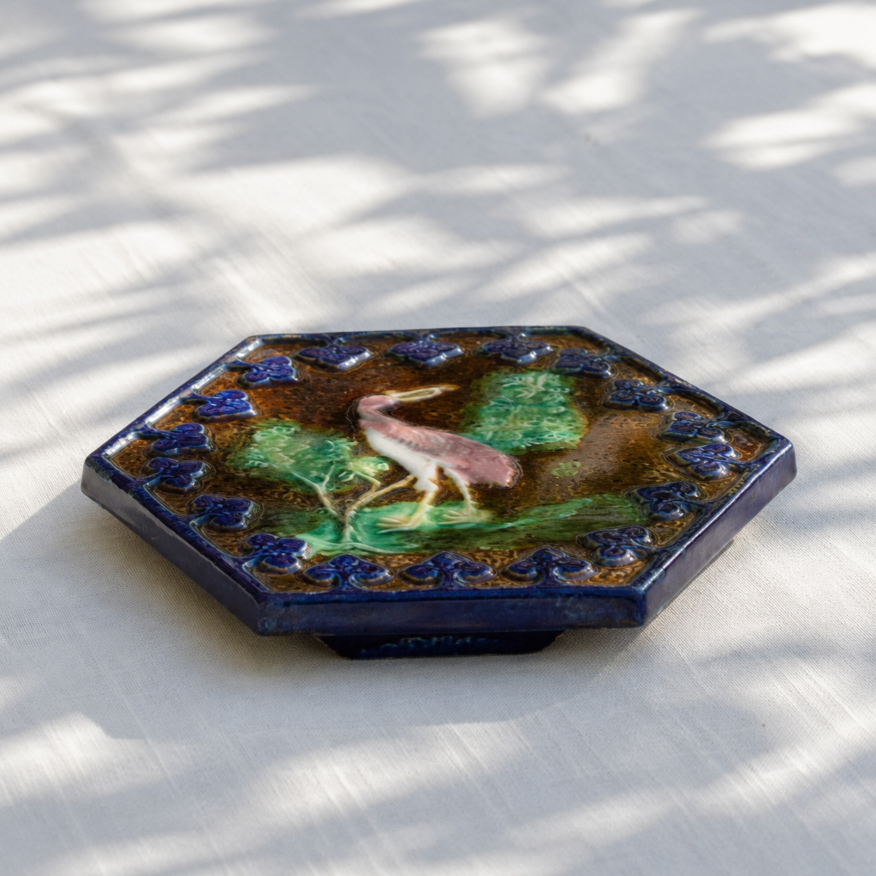Dessous de plat XIXe en barbotine polychrome oiseau rose